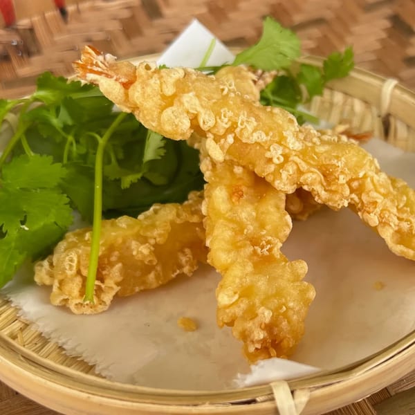 Crispy fried shrimp tempura with fresh green cilantro, served in a bamboo basket.