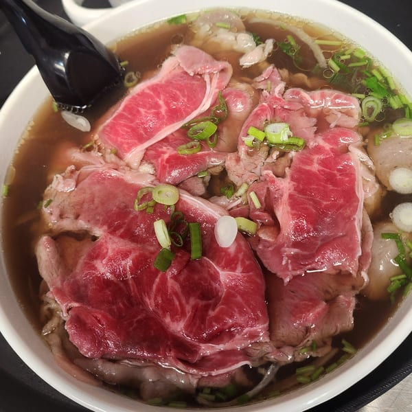 Close-up of Pho Akaushi Orlando's Vietnamese pho with rare beef, scallions, and broth.